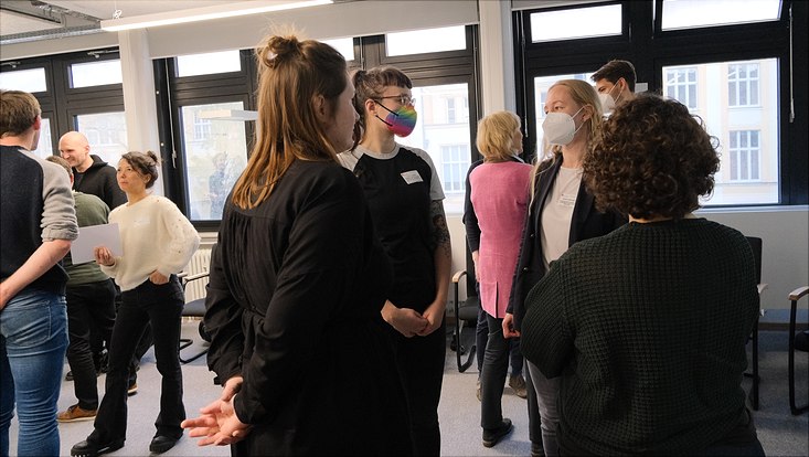 Warm-Up Verstetigungsworkshop: Viele Personen stehen im Raum und unterhalten sich