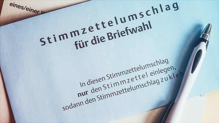 Auf dem Bild sind ein Stimmzettelumschlag sowie ein Kugelschreiber zu sehen.
