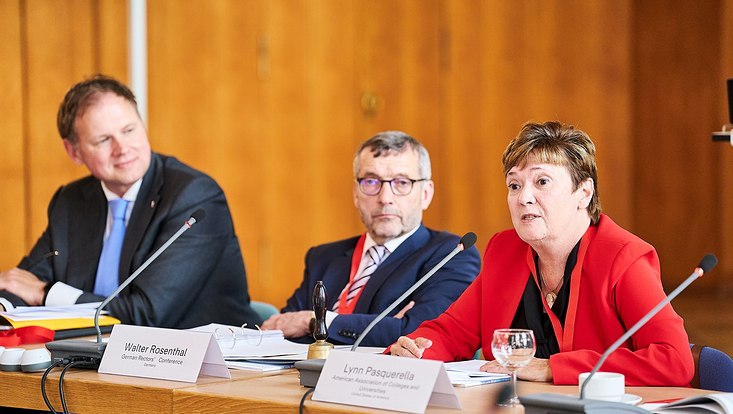 GUC 2023 Der Universitätspräsident Hauke Heekeren und zwei weitere Personen sitzen an Tischen. Vor ihnen steht jeweils ein Mikrofon. Auf den Tischen befinden sich Namensschilder und Unterlagen.