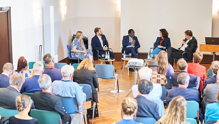 GUC 2023 Fünf Personen sitzen vor einem Publikum und sprechen miteinander.