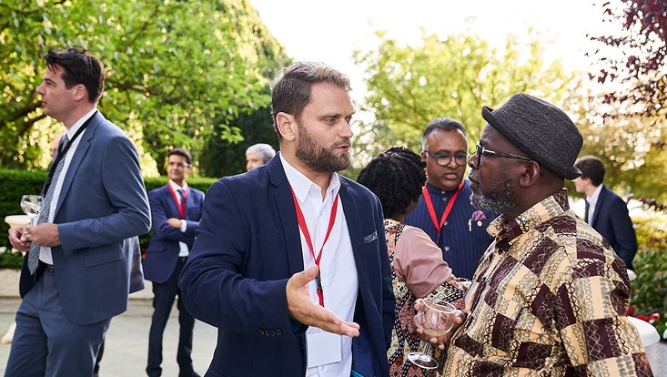 GUC 2023 Im Vordergrund unterhalten sich zwei Personen. Im Hintergrund stehen weitere Personen.