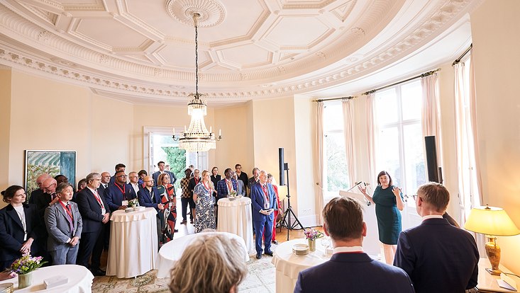 GUC 2023 Rechts steht eine Frau an einem Mikrofon und spricht. Rechts und links von ihr steht das Publikum.