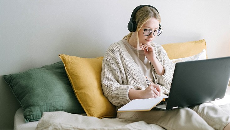 Frau mit Laptop und Notizheft