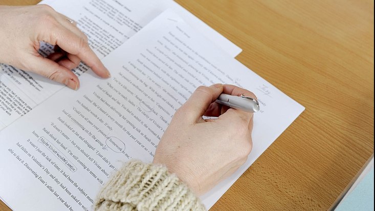 Man sieht zwei Hände, eine hält einen Stift und kommentiert einen ausgedruckten Text.