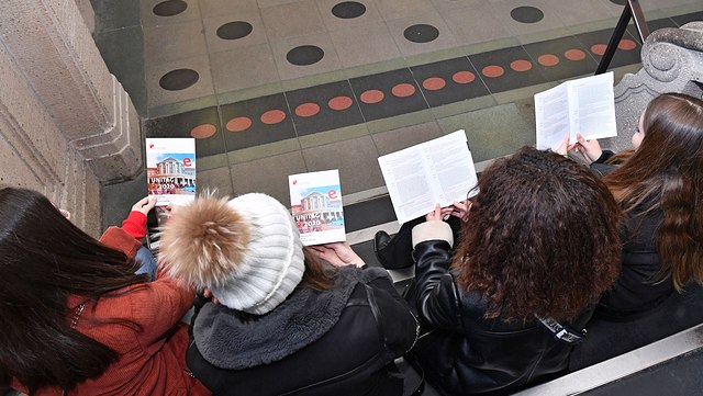 Vier Schülerinnen sitzen zusammen und schauen sich Unitag-Broschüren an