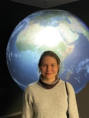 Susanne Fuchs, standing in front of satellite data projected onto a globe.