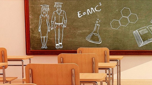 Ein Klassenzimmer mit Tischen und Stühlen. Vorne ist eine Tafel mit Kreidezeichnungen.