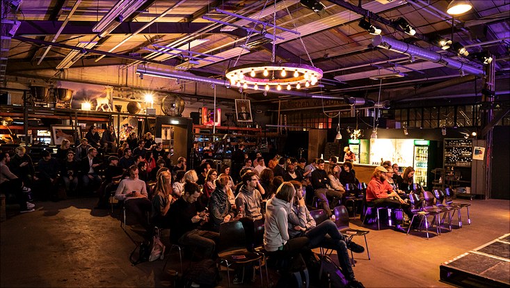 Three Minute Thesis 2022 Die Zuschauer der 3MT Veranstaltung sitzen auf Stühlen und schauen zur Bühne.