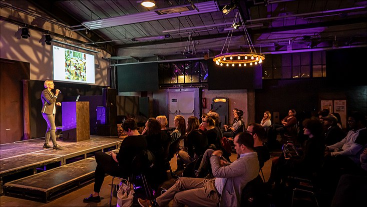 Three Minute Thesis 2022 Eine kleine Bühne und davor das Publikum.