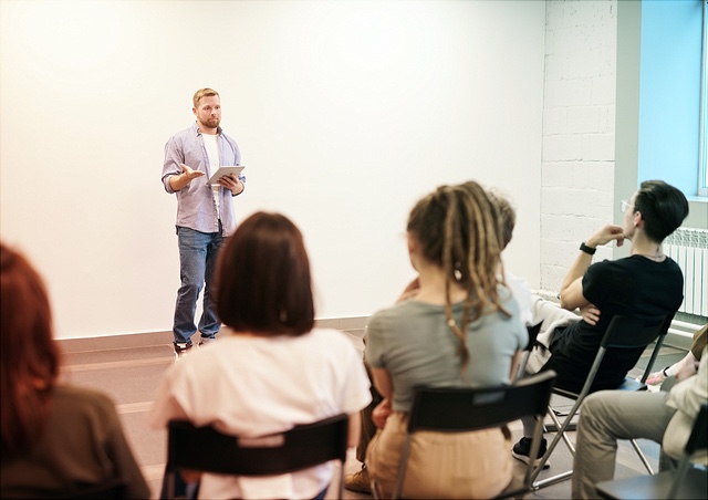 Studierende lauschen interessiert einem jungen Mann