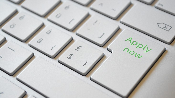 Ausschnitt einer Laptop-Tastatur und auf der Enter-Tastatur steht "Apply Now"