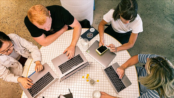 Vogelperspektive auf Gruppe am Tisch mit Laptops