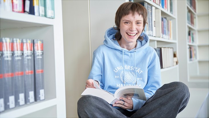 Unitag: Arbeiterkind Studierende in der Bibliothek mit einem Buch in der Hand.