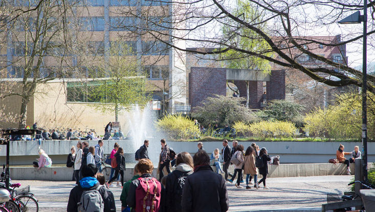 Das illustrative Bild zeigt Studierende auf dem Campus vor dem Gebäude VMP6