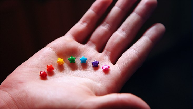 Hand holding rainbow colored star candy.