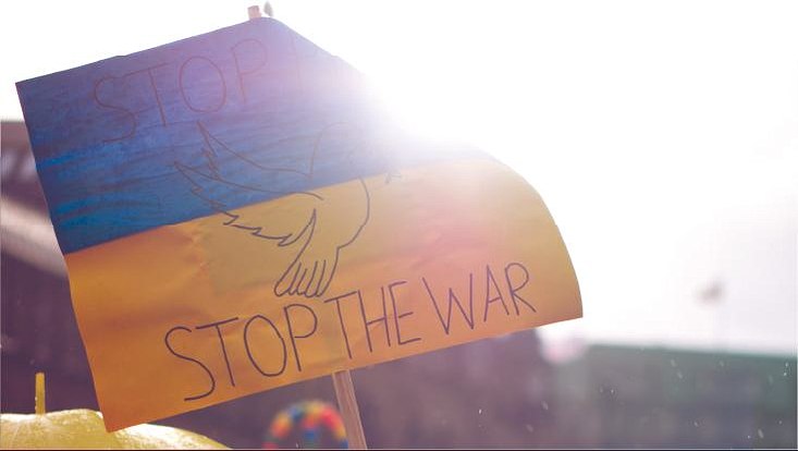 Man sieht eine ukrainische Flagge, auf der das Statement: Stop the war zu lesen ist