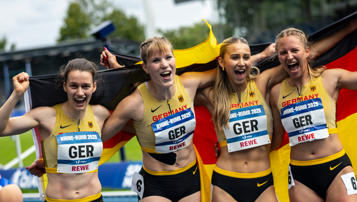 4 Sprinterinnen strahlen nach Lauf und halten Deutschlandfahne