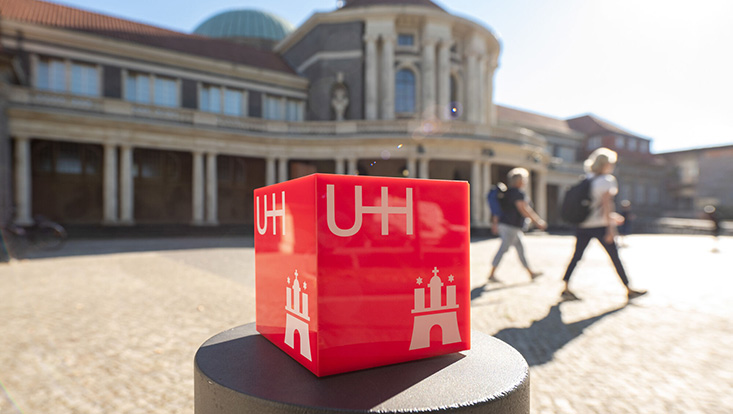 Blick auf Uni Hauptgebäude, im Vordergrund roter Würfel