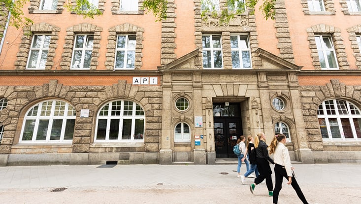 Personen laufen an Eingang von AP1 (Pferdestall) vorbei