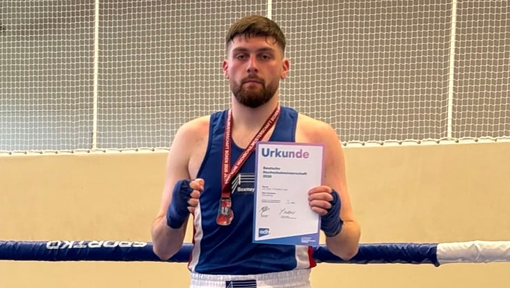 Enis Terstena päsentiert seine Medaille und Urkunde
