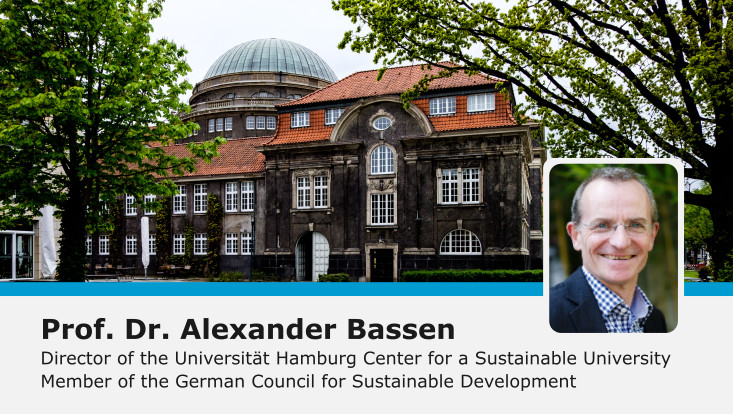 Alexander Bassen eingeklingt vor Hintergrund mit Bäumen und Stele 'Kompetenzzentrum Nachhaltige Universität'