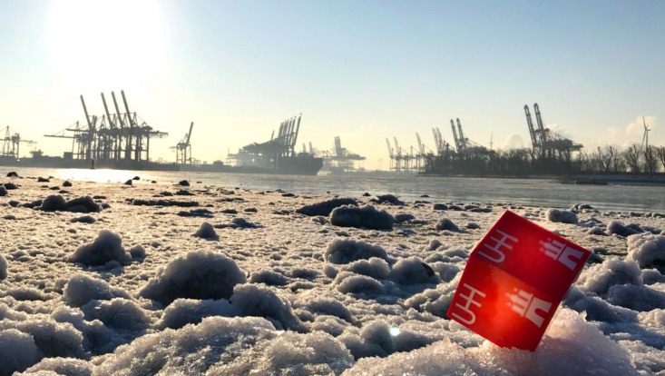 UHH-Würfel auf Eis im Vordergrund, Hafen im Hintergrund