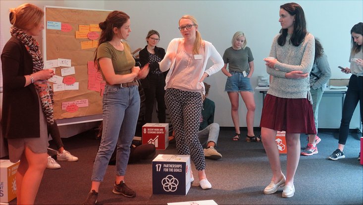 Eine Gruppe Studierender steht zusammen und diskutiert.