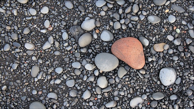graue Kiesel, in der Mitte ein großer roter runder Stein