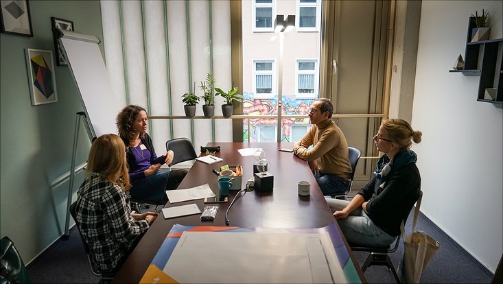 Vier Teilnehmende sitzen um einen Tisch herum und diskutieren über das Thema ihrer Session.