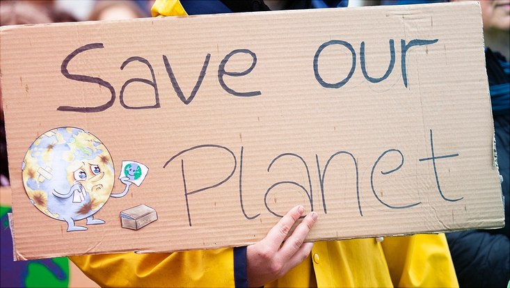 Ein Plakat mit der Aufschrift "Save our Planet" wird hochgehalten.