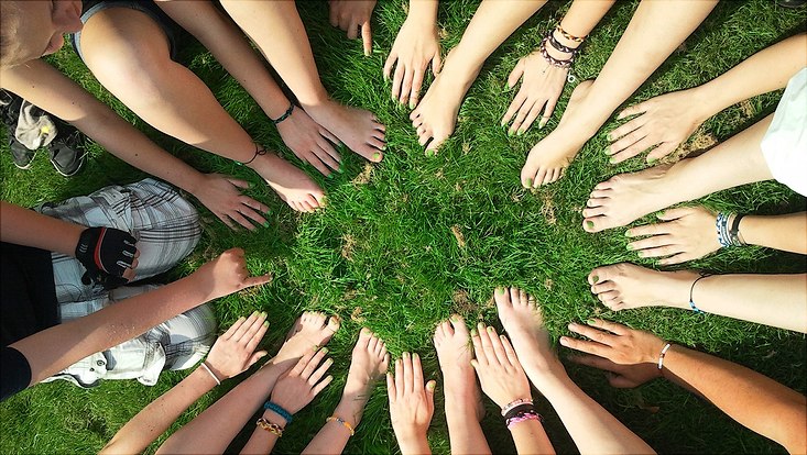 Viele Füße und Hände bilden einen Kreis auf einer Rasenfläche