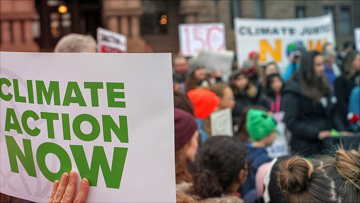 Auf einer Demonstration wird das Plakat "Climate Actio Now" hoch gehalten.