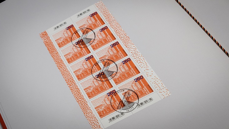 Das Foto zeigt einen gestempelten Bogen der Sondermarke mit dem Wert 2,60 EURO. Auf der in Rot gehaltenen Briefmarke ist der linke Teil des Hauptgebäudes zu sehen, in einer gepunkteten Darstellung, die vielleicht an einen QR-Code erinnern soll.