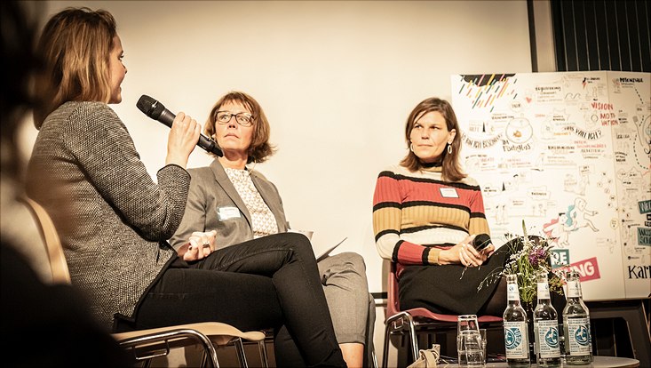 Eine Teilnehmerin sitzt auf dem Podium und diskutiert mit.