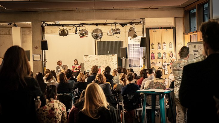 Die Teilnehmende sitzen vor einer kleinen Bühne, auf der ein Karrieretalk mit Dr. Muriel Helbig, Präsidentin der TH Lübeck, stattfindet.