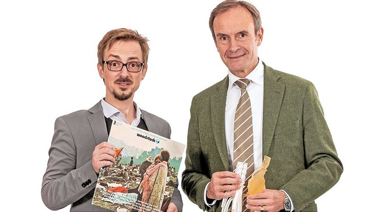 Kai Stefan Lothwesen hält ein Woodstock-Album als Schallplatte in den Händen und Eike Sebastian Debus das Kunststoffmodell einer Hauptschlagader mit Aneurysma sowie eine Hybridprothese.